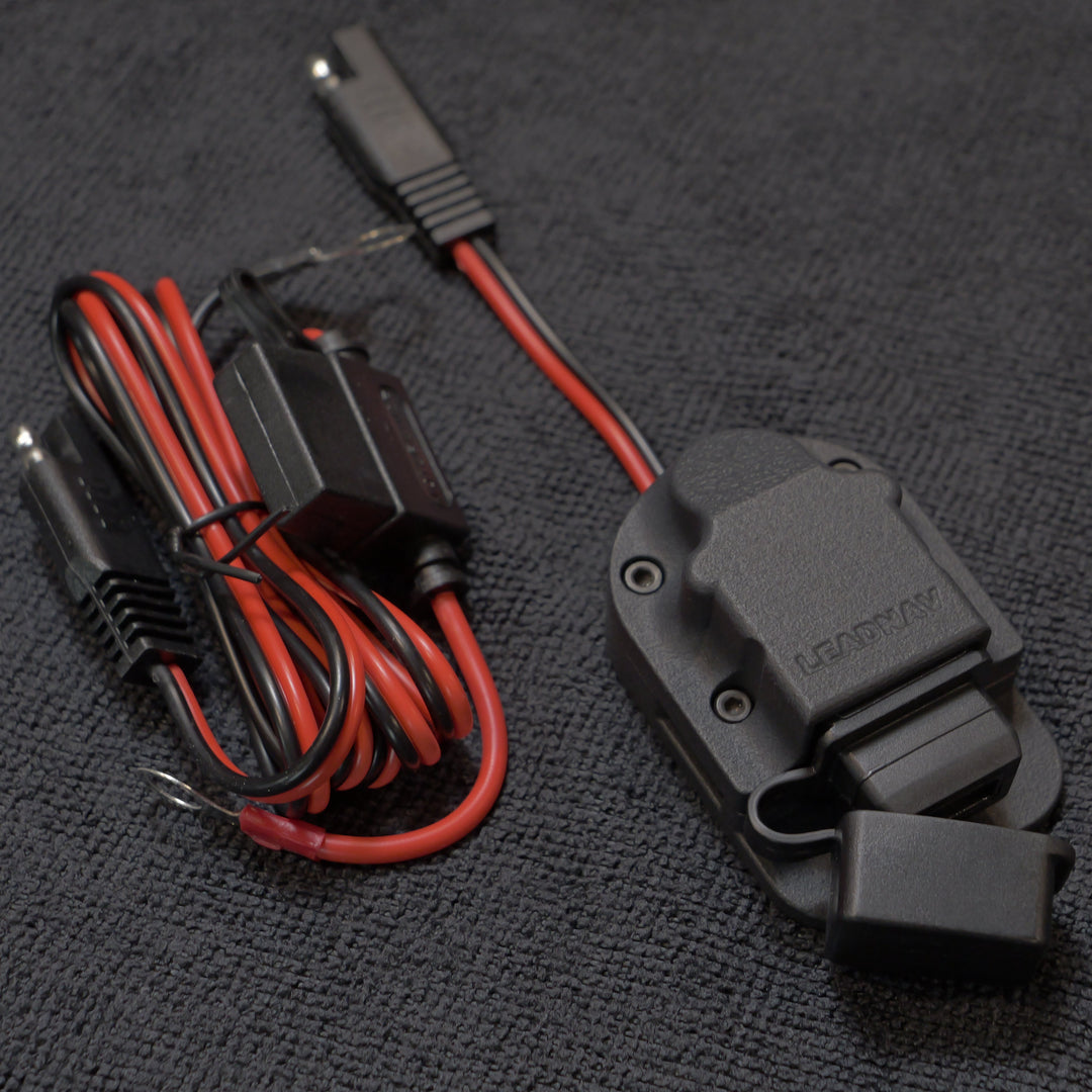 Car charger with red and black wiring on a dark textured surface